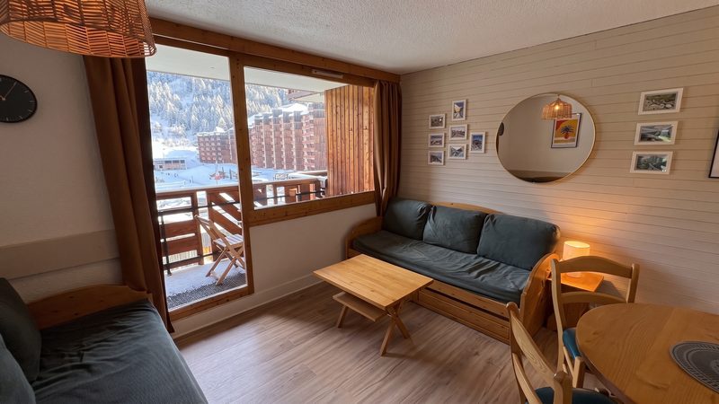 Le séjour : canapés, table à manger et porte-fenêtre ouvrant sur le balcon avec vue sur la montagne